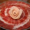 Assiette de jambon ibérique Cebo de Campo finement tranché, révélant sa texture marbrée et sa couleur rouge intense.